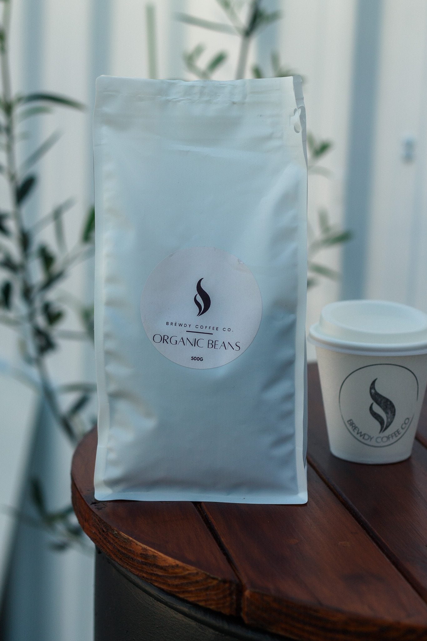Organic Beans pouch beside a Brewdy takeaway cup at the cafe