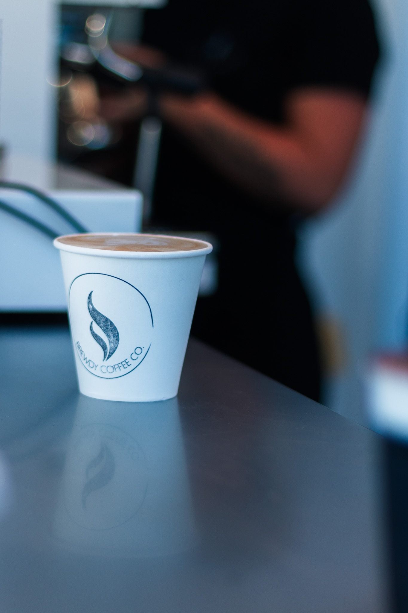 Brewdy stamped takeaway cup with latte art on the cafe counter