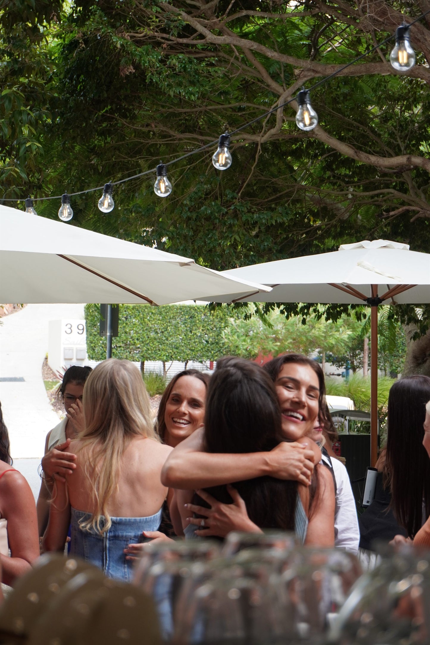 Friends embracing at a Brewdy community event under festoon lights